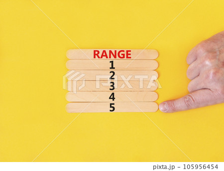 Time to range 5 symbol. Concept word Range 1 2 3 4 5 on wooden sticks. Businessman hand. Beautiful yellow table yellow background. Business planning and time to range 5 concept. Copy space. 105956454