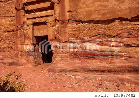 View of the wall with the door, the entrance to the temple, carved into the red sandstone rock in the canyon. Petra, Jordan View of the wall with the door, the entrance to the temple, carved into the red sandstone rock in the canyon. Petra, Jordan 105957482
