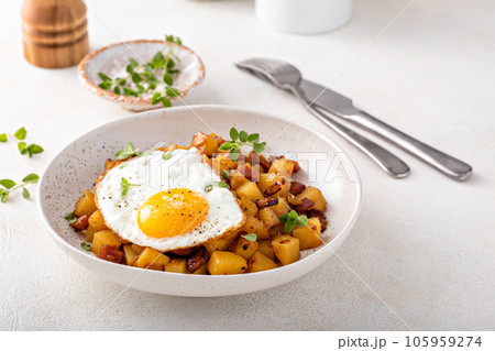 Potato, onion and ham hash topped with fried egg Potato, onion and ham hash topped with fried egg 105959274