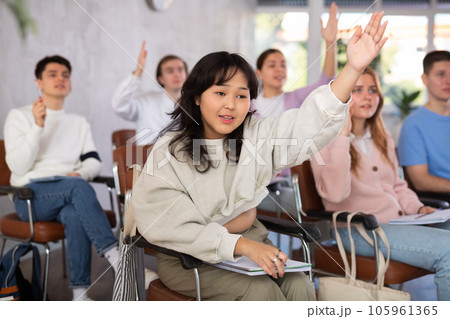 Group of high school students raising hands in auditorium 105961365