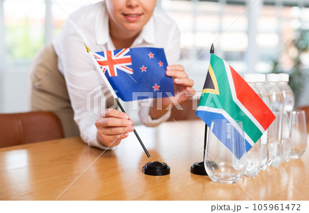 Preparing for business presentation - secretary places flags of Australia and South Africa on negotiating table Preparing for business presentation - secretary places flags of Australia and South Africa on negotiating table 105961472