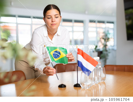 Young lady sets miniatures flags of Netherlands and Brazil for international negotiations Young lady sets miniatures flags of Netherlands and Brazil for international negotiations 105961704