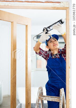 Cheerful woman construction worker using spray foam 105961770
