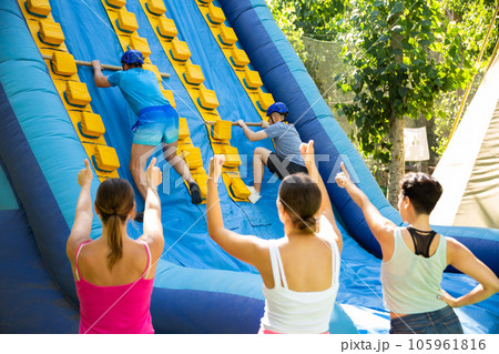 Two men climbing on inflatable castle with wooden sticks 105961816