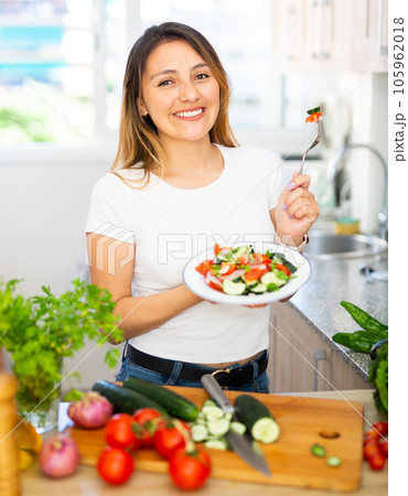 Young female holding plate of fresh vegetable salad at kitchen Young female holding plate of fresh vegetable salad at kitchen 105962018