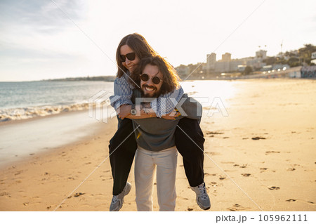 Handsome couple in love hugging while walking along the beach on sunny day Handsome couple in love hugging while walking along the beach on sunny day 105962111