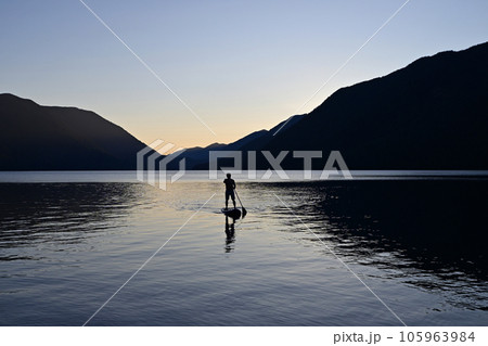 Silhouetted male paddleboarder on Lake Crescent in Olympic National Park. Silhouetted male paddleboarder on Lake Crescent in Olympic National Park. 105963984