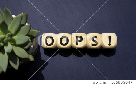 Oops symbol. Concept word Oops on wooden cubes. Beautiful deep blue background with succulent plant. Business and Oops concept. Copy space. Oops symbol. Concept word Oops on wooden cubes. Beautiful deep blue background with succulent plant. Business and Oops concept. Copy space. 105965647