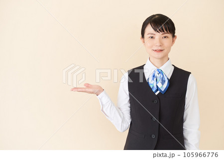 手で案内するベストにリボンタイの制服を着た、受付業務、事務業務の女性 手で案内するベストにリボンタイの制服を着た、受付業務、事務業務の女性 105966776