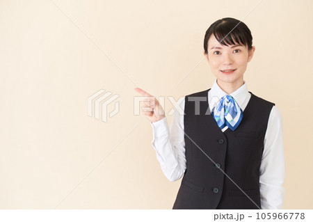 指で指し示すベストにリボンタイの制服を着た、受付業務、事務業務の女性 指で指し示すベストにリボンタイの制服を着た、受付業務、事務業務の女性 105966778