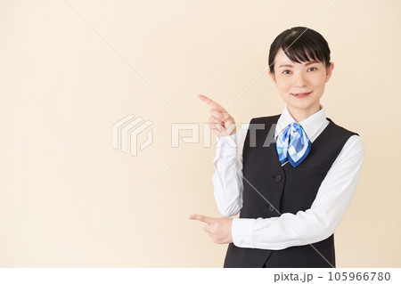 指で指し示すベストにリボンタイの制服を着た、受付業務、事務業務の女性 指で指し示すベストにリボンタイの制服を着た、受付業務、事務業務の女性 105966780