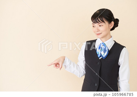 指で指し示すベストにリボンタイの制服を着た、受付業務、事務業務の女性 指で指し示すベストにリボンタイの制服を着た、受付業務、事務業務の女性 105966785