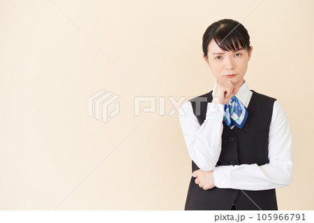 考えるポーズをするベストにリボンタイの制服を着た、受付業務、事務業務の女性 考えるポーズをするベストにリボンタイの制服を着た、受付業務、事務業務の女性 105966791
