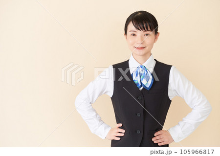 腰に手を当てるベストにリボンタイの制服を着た、受付業務、事務業務の女性 腰に手を当てるベストにリボンタイの制服を着た、受付業務、事務業務の女性 105966817