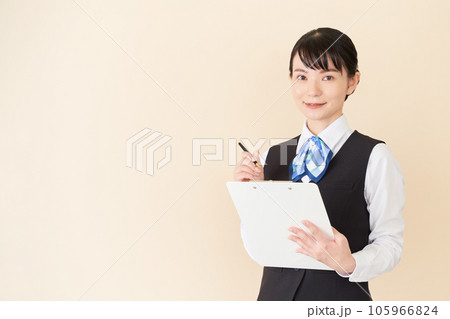 書類を書くベストにリボンタイの制服を着た、受付業務、事務業務の女性 書類を書くベストにリボンタイの制服を着た、受付業務、事務業務の女性 105966824