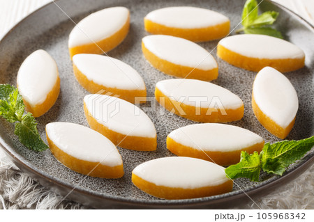 Provencal french Calisson sweets from melon, almond and orange covered with white royal icing close-up in a plate. Horizontal Provencal french Calisson sweets from melon, almond and orange covered with white royal icing close-up in a plate. Horizontal 105968342