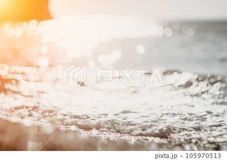 Blurred golden sea at sunset. The sun reflects and sparkles on the waves with bokeh, illuminating the golden sea. Holiday recreation concept. Abstract nautical summer ocean sunset nature background. Blurred golden sea at sunset. The sun reflects and sparkles on the waves with bokeh, illuminating the golden sea. Holiday recreation concept. Abstract nautical summer ocean sunset nature background. 105970513