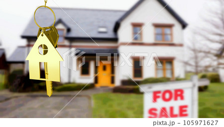 Image of gold house key fob and key, hanging in front of blurred house with for sale sign 105971627