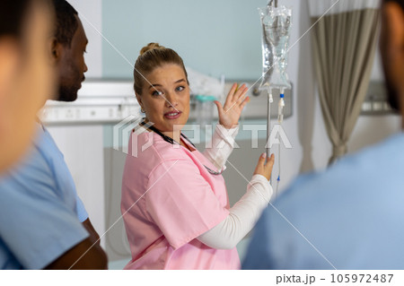Caucasian female doctor with diverse trainee doctors applying drip at hospital Caucasian female doctor with diverse trainee doctors applying drip at hospital 105972487