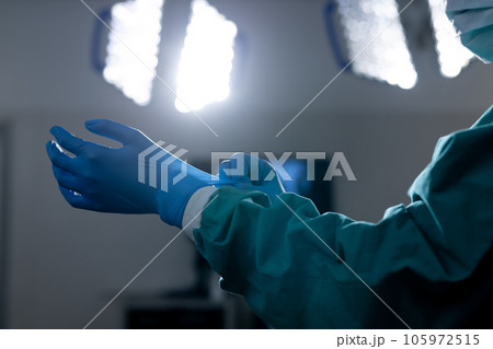 African american female surgeon wearing surgical gown and gloves in operating theatre at hospital African american female surgeon wearing surgical gown and gloves in operating theatre at hospital 105972515