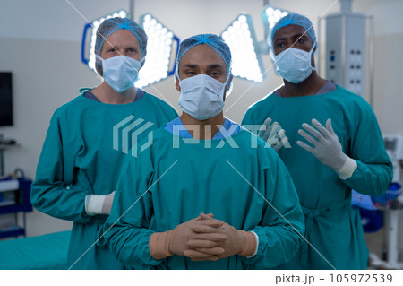 Portrait of diverse male surgeons wearing surgical gowns in operating theatre at hospital Portrait of diverse male surgeons wearing surgical gowns in operating theatre at hospital 105972539