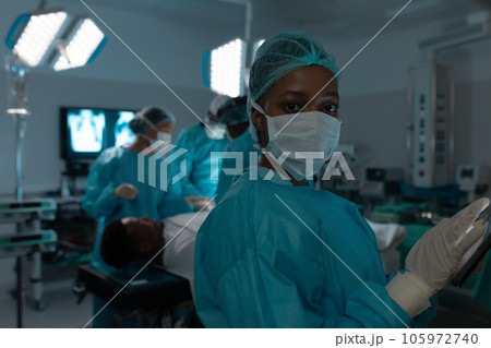 Portrait of african american female surgeon wearing surgical gown in operating theatre at hospital Portrait of african american female surgeon wearing surgical gown in operating theatre at hospital 105972740