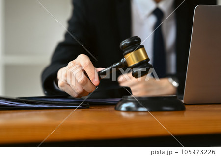 Unrecognizable judge holding gavel to bang on sounding block. Lawyer, justice and law, attorney concept. Unrecognizable judge holding gavel to bang on sounding block. Lawyer, justice and law, attorney concept. 105973226
