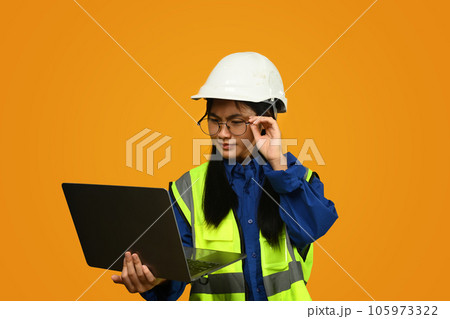 Asian girl wearing helmet holding laptop isolated on yellow background, future dream job career as engineer and architect. 105973322