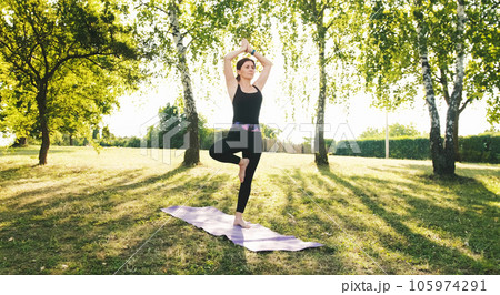 Fitness athletic Girl practicing yoga Outdoors standing standing on a one leg pose and practicing meditation. Body and mental health concept. 105974291
