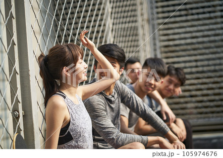 hipster young asian adults resting outdoors at a basketball court after exercise hipster young asian adults resting outdoors at a basketball court after exercise 105974676