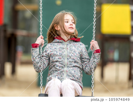 Cute little girl riding a chain swing in a autumn park 105974849