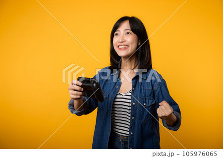 Portrait young asian woman with happy success smile wearing denim clothes holding joystick controller and playing video game. Fun and relax hobby entertainment lifestyle concept. Portrait young asian woman with happy success smile wearing denim clothes holding joystick controller and playing video game. Fun and relax hobby entertainment lifestyle concept. 105976065