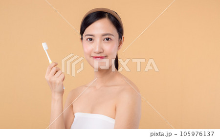 portrait beauty young woman with healthy happy smile holding toothbrush in her hand at morning isolated on beige studio background. hygiene tooth mouth clean care and dental concept. portrait beauty young woman with healthy happy smile holding toothbrush in her hand at morning isolated on beige studio background. hygiene tooth mouth clean care and dental concept. 105976137