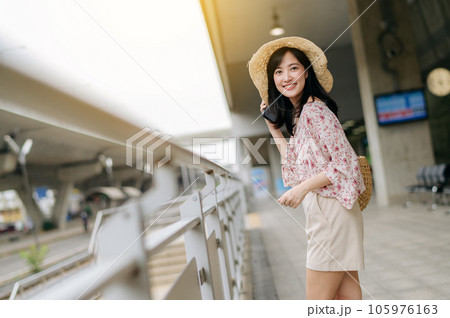 Asian young woman traveler with weaving basket using a mobile phone beside railway train station in Bangkok. Journey trip lifestyle, world travel explorer or Asia summer tourism concept. Asian young woman traveler with weaving basket using a mobile phone beside railway train station in Bangkok. Journey trip lifestyle, world travel explorer or Asia summer tourism concept. 105976163