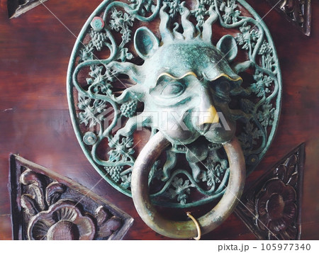 A door knocker is a fixture on the front door of a house. It is made of metal and has the form of a ring, which is knocked on the metal part of the door knocker fixed to the wall. Muzzle of a lion. A door knocker is a fixture on the front door of a house. It is made of metal and has the form of a ring, which is knocked on the metal part of the door knocker fixed to the wall. Muzzle of a lion. 105977340