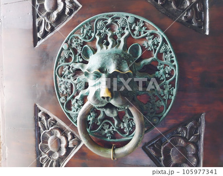 A door knocker is a fixture on the front door of a house. It is made of metal and has the form of a ring, which is knocked on the metal part of the door knocker fixed to the wall. Muzzle of a lion. 105977341