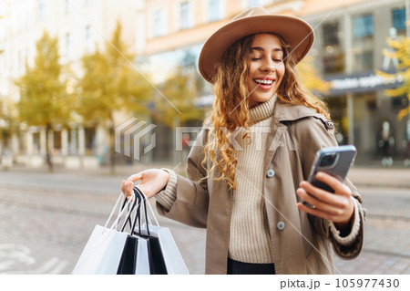 Happy woman with shopping bags walking on street. Purchases, black friday, discounts, sale concept. Happy woman with shopping bags walking on street. Purchases, black friday, discounts, sale concept. 105977430