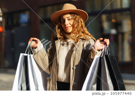 Happy woman with shopping bags walking on street. Purchases, black friday, discounts, sale concept. 105977440