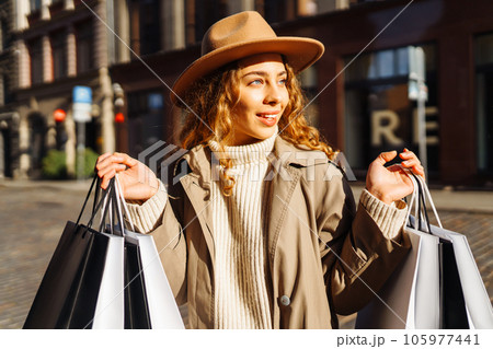 Happy woman with shopping bags walking on street. Purchases, black friday, discounts, sale concept. Happy woman with shopping bags walking on street. Purchases, black friday, discounts, sale concept. 105977441