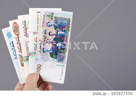 Algerian dinar in the hand on a gray background 105977550