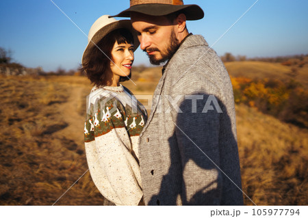 Lovely hipster couple looking at each other. Couple wearing beautiful hats and sweaters. 105977794