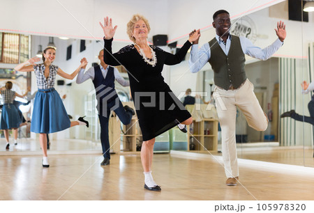 Woman pensioner with african man practising charleston 105978320