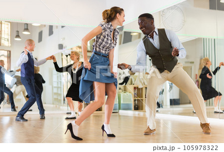 Woman with african man practising charleston dancing Woman with african man practising charleston dancing 105978322