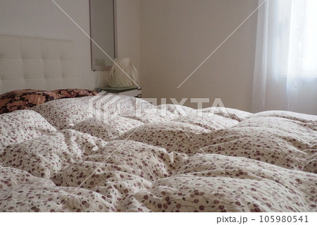 Double bridal bed with pillows and thick feather duvet. Bedroom design. Soft white headboard. Interior with furniture and bedding 105980541
