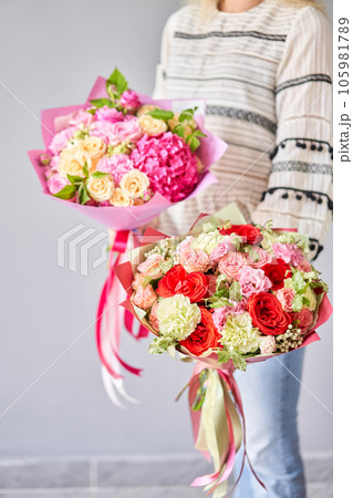 Two Small Beautiful bouquets of mixed flowers in woman hand. Floral shop concept . Beautiful fresh cut bouquet. Flowers delivery 105981789