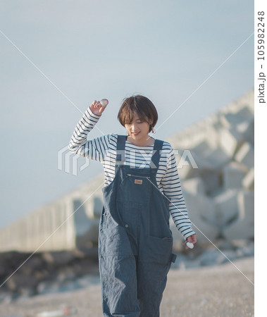 海辺ででオーバーオールの女の子が貝殻を持って歩いてる 海辺ででオーバーオールの女の子が貝殻を持って歩いてる 105982248