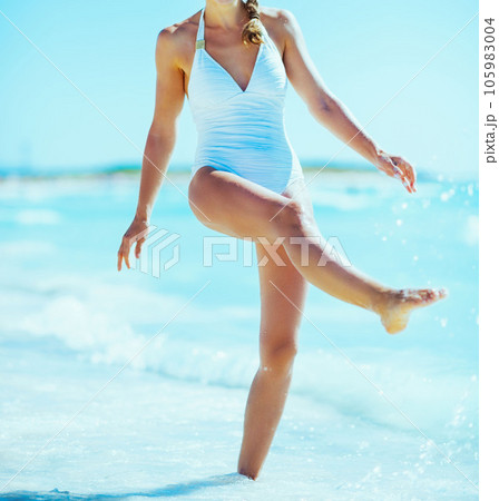 Happy young woman playing with water on beach 105983004