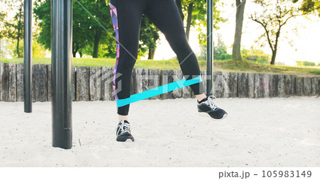 Fitness girl doing workout legs exercises with rubber elastic strap band Fitness girl doing workout legs exercises with rubber elastic strap band 105983149