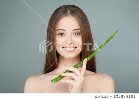 Happy smiling woman with healthy fresh clear skin holding green aloe vera leaf in her hand. Happy smiling woman with healthy fresh clear skin holding green aloe vera leaf in her hand. 105984183