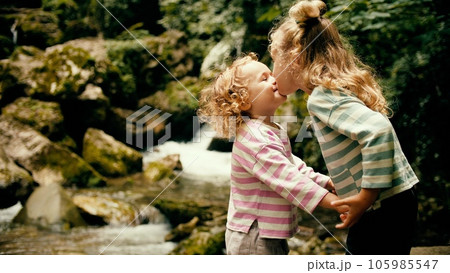 Little sisters hug each other at beautiful waterfall in the woods 105985547